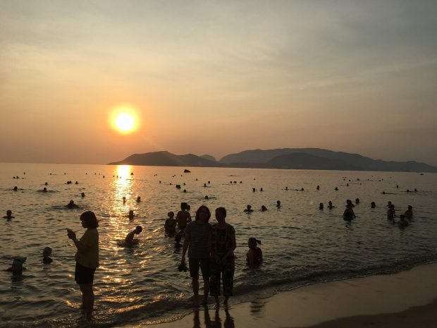 People swim at a beach in Nha Trang City on an early morning in late May